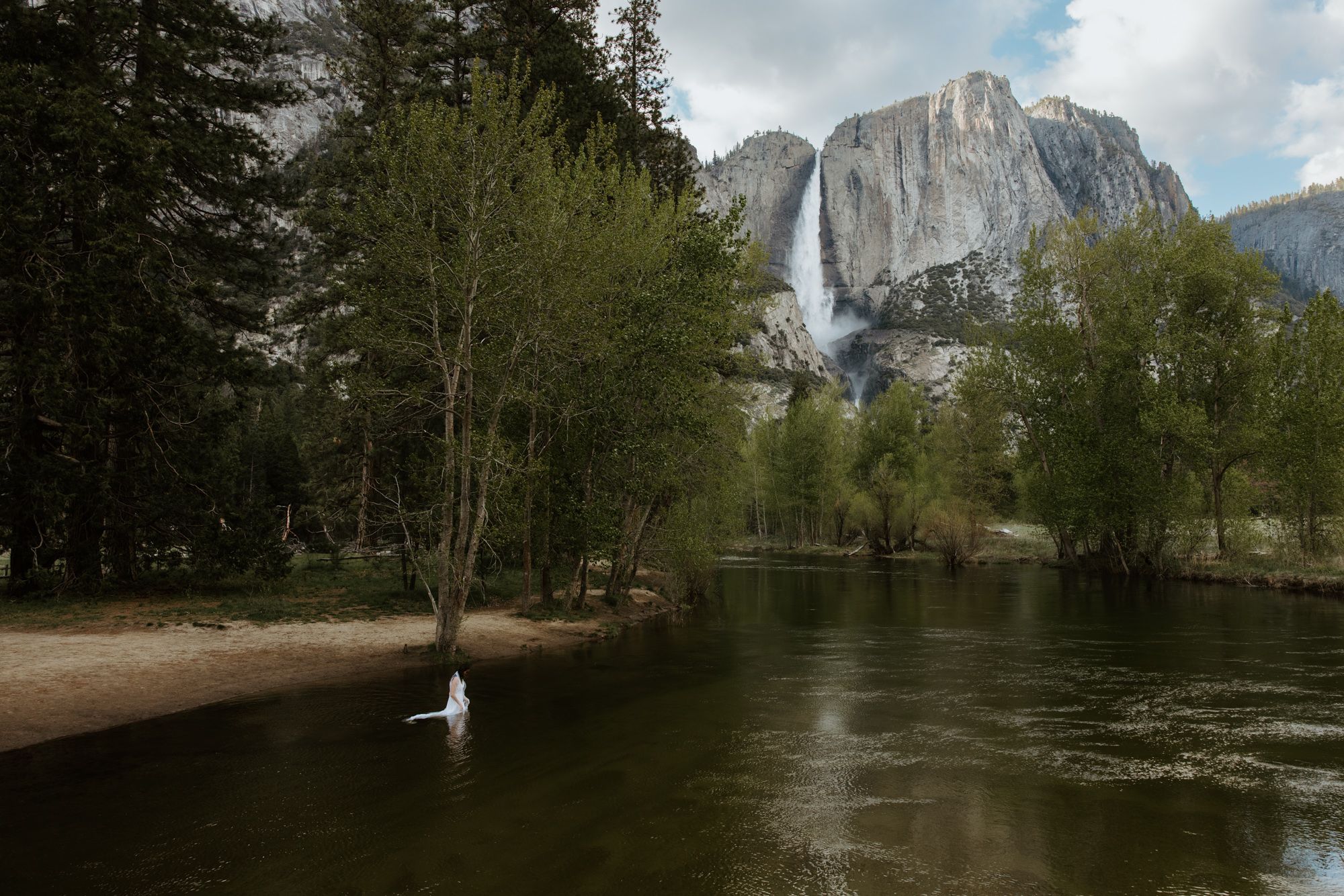 Adventurous bride stepping into the river during Yosemite elopement — intimate and wild wedding moment